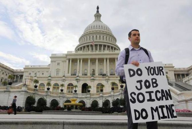 A furloughed federal employee holds a sign on the steps to the US Capitol after the government shut down, on Capitol Hill.