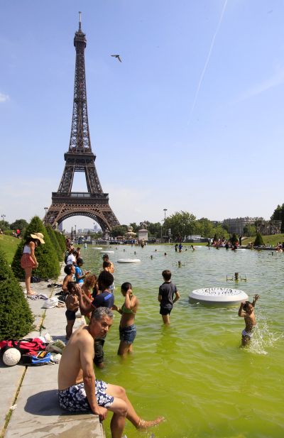 Tourists cool off in the Trocadero fountains near the Eiffel tower on a hot summer day in Paris.