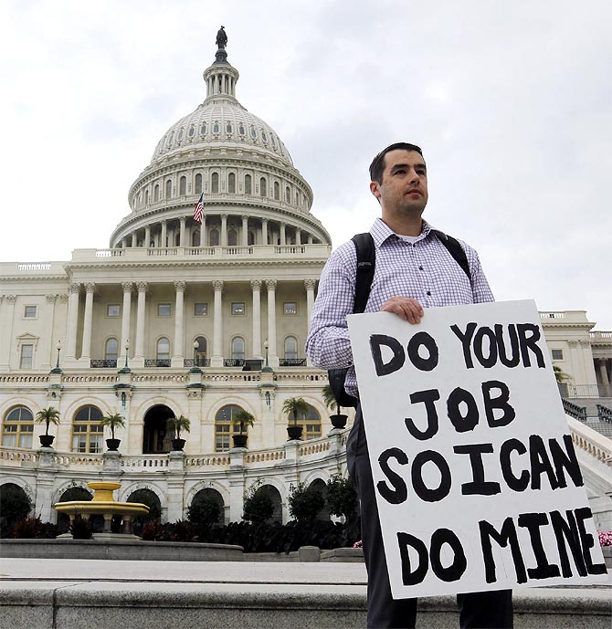 A furloughed federal employee holds a sign on the steps to the U.S. Capitol after the government shut down, on Capitol Hill.