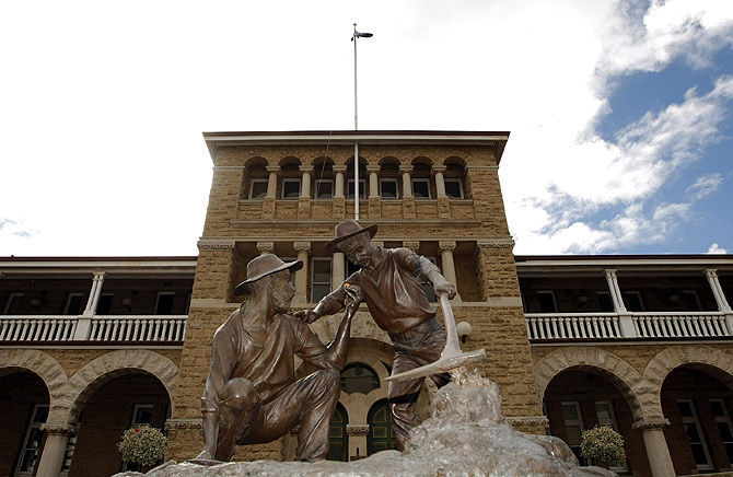 A statue which depicts miners striking gold stands in front of the Perth Mint.