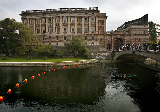 A fisherman lifts his net from a canal next to Sweden's Riksdagshuset, or Parliament.