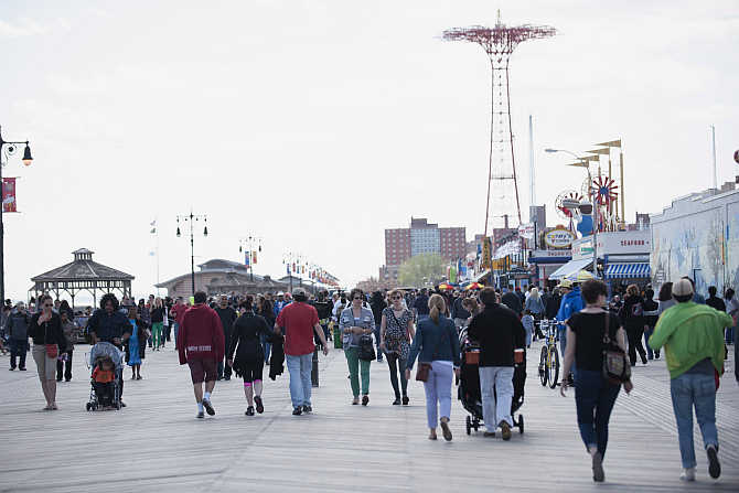 People make their way along the boardwalk in Coney Island in the Brooklyn Borough of New York, United States.