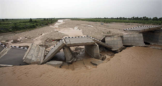 A bridge built over a stream leading to the river Tawi is damaged by flash floods on the outskirts of Jammu.
