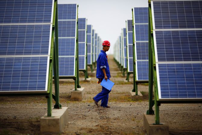 A worker inspects solar panels at a solar farm.