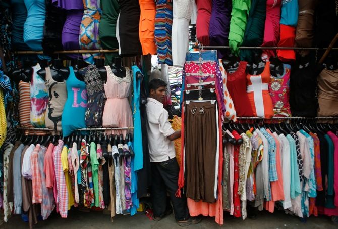 A salesman waits for customers at a roadside store selling clothes at a market in Mumbai.
