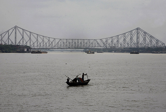 Fishermen row a boat on the Hooghly River against the backdrop of Howrah bridge in the eastern Indian city of Kolkata.