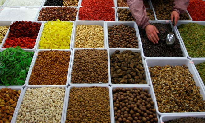 A vendor sells dry fruits and nuts at a market.