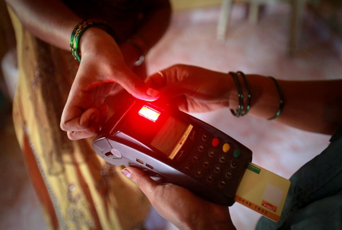 Karuna Prakash Mukudum, a coordinator working for Financial Information Network and Operations Ltd (FINO), processes a smart card as she collects money from a woman in Wavanje village of Raigad district.