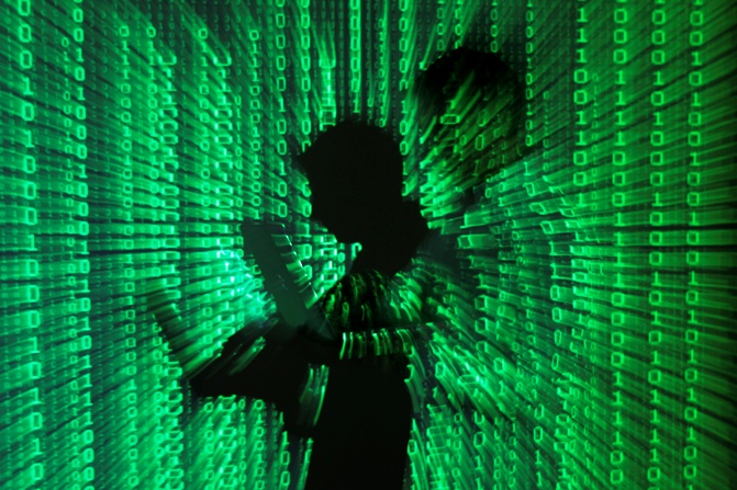 An illustration picture shows a projection of binary code on a man holding a laptop.