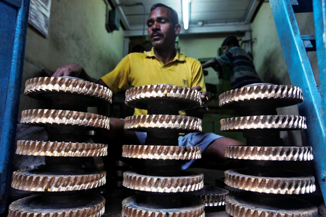 A worker cleans gear wheels used in conveyor belts at a small scale factory in Kolkata.