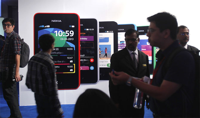 Visitors gather during the unveiling of Nokia's $99 phone in its mid-range Asha line.