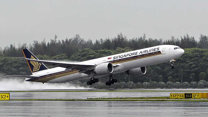 A Singapore Airlines Boeing 777-300ER passenger jet takes off in the rain at Changi Airport in Singapore.