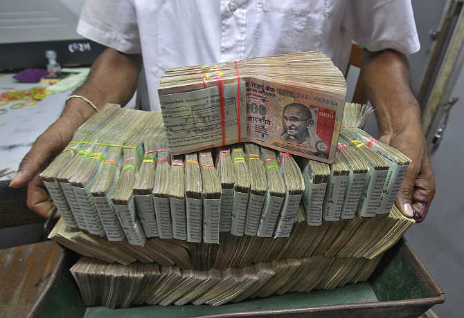 An employee poses with the bundles of rupee notes inside a bank in Agartala, Tripura.