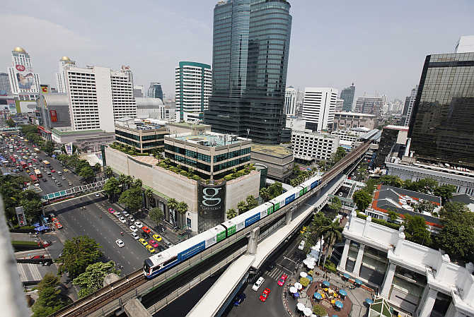 A skytrain passes over vehicles on road in Bangkok, Thailand.