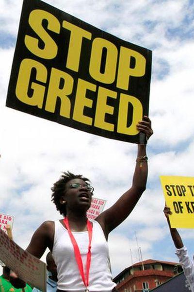 Protestors carry placards as they participate in a demonstration against lawmakers' salary demands near parliament buildings in the capital Nairobi.