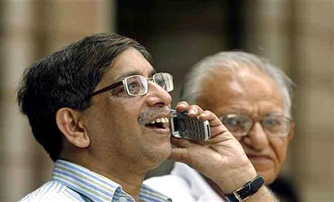 A man speaks on a phone as he looks at a large screen displaying India's benchmark share index on the facade of the Bombay Stock Exchange.