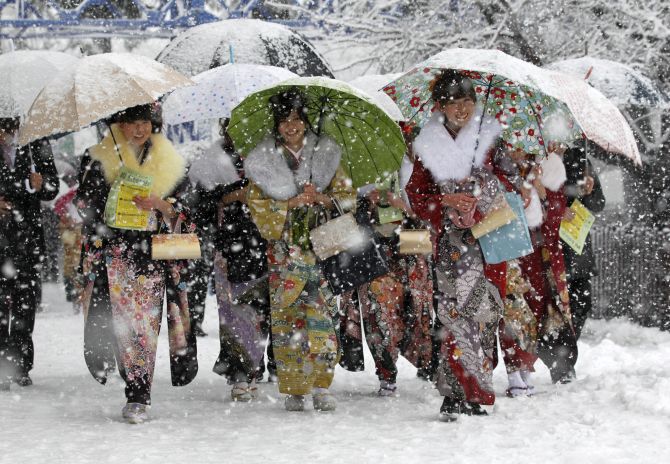 Japanese women in kimonos walk to attend a ceremony celebrating Coming of Age Day in heavy snowfall at Toshimaen amusement park in Tokyo.