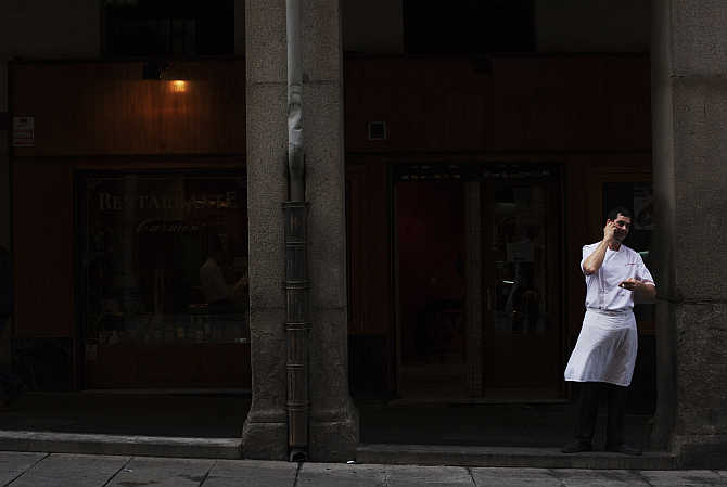 A cook takes a break as he talks on the phone in central Madrid, Spain.