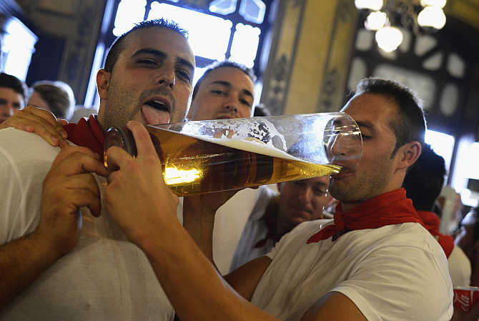 Revellers drink beer from a giant glass during San Fermin festival in Pamplona, Spain.