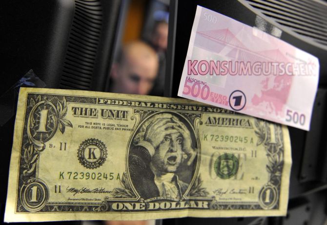 A  share trader is pictured behind a mock one dollar bill and a mock 500 Euro note symbolizing a consumer credit note, at the German stock exchange in Frankfurt.