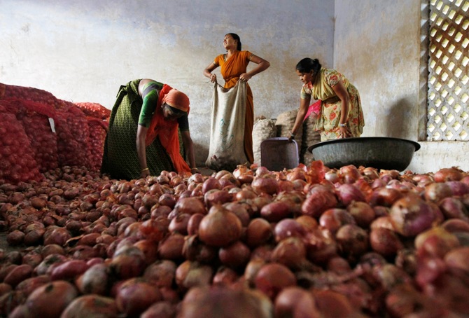 Workers fill sacks with onions after sorting them at a wholesale market in Ahmedabad.