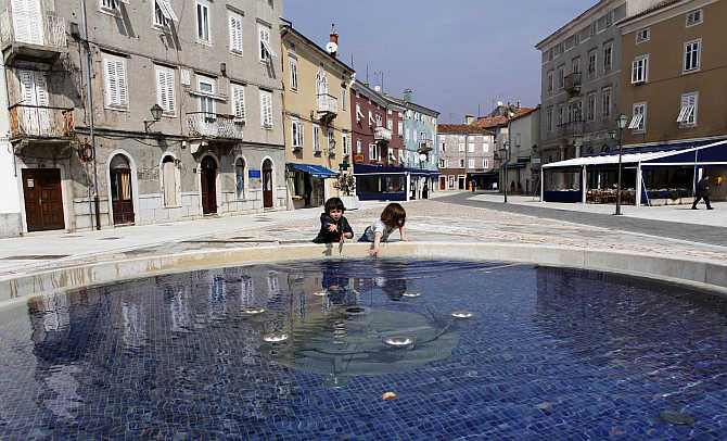 Children play near a public fountain in Rijeka on the northern Adriatic island of Cres, Croatia.