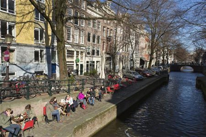 People sit on a quay at the Leliegracht canal in Amsterdam. 