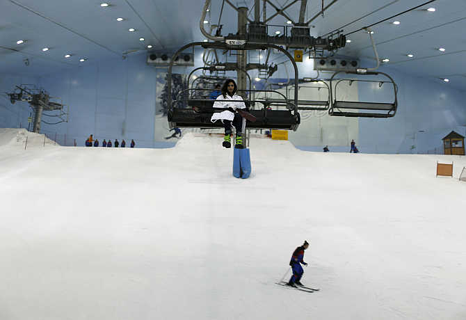 Visitors ski and ride in chairlifts in mountain-themed ski park at Emirates Mall in Dubai, United Arab Emirates.