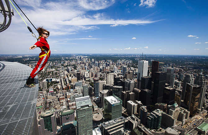 A reporter leans over the edge of the catwalk during the media preview of the 'EdgeWalk' on the CN Tower in Toronto, Canada.