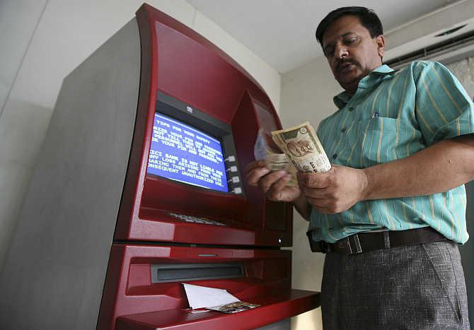 A man counts money after withdrawing it from an ATM in Jammu.