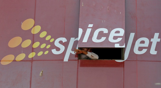 A man looks out through a window with an advertisement of SpiceJet Airline, on a commercial building in Ahmedabad.