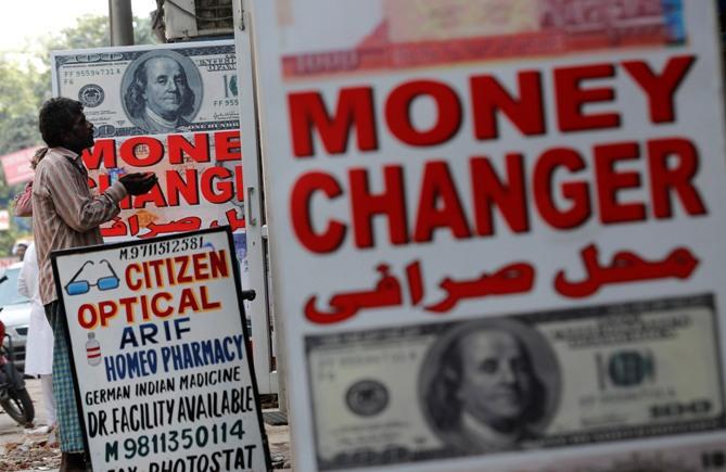 A man begs outside a currency exchange shop in New Delhi.