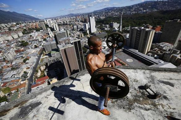Gabriel Rivas, 30, lifts weights on a balcony on the 28th floor of the Tower of David skyscraper.