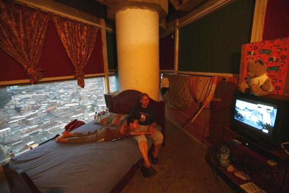Adriana Gutierrez and her son Carlos Adrian watch TV as they sit on their bed in their 24th floor apartment.