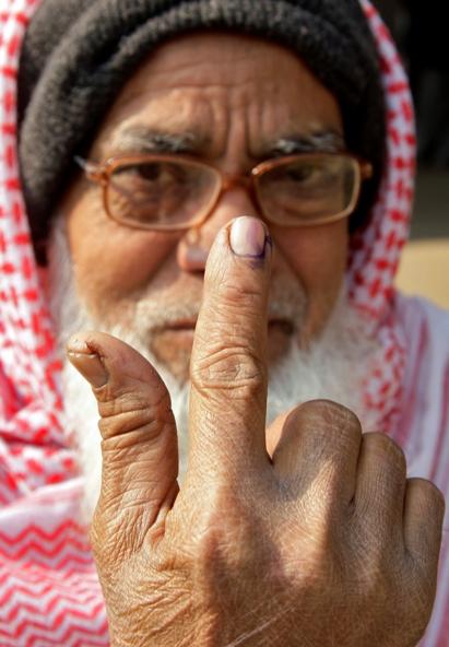 A voter shows his ink-marked finger after casting his vote, outside a polling station.