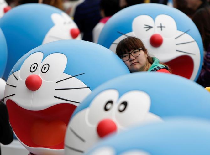 A visitor poses for a photo next to a Doraemon model during an exhibition in Beijing.