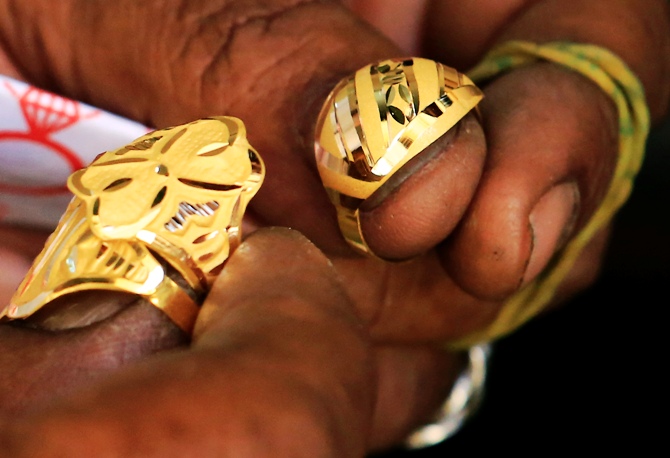A goldsmith holds on to gold rings at the gold market.