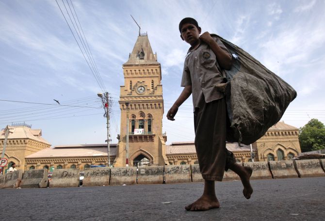 A barefooted boy carries a sack for recyclable materials as he walks past the British era Empress Market building in Karachi.