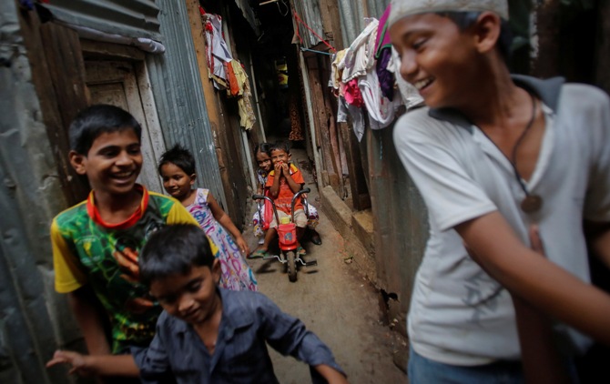 A boy rides his tricycle as others play inside a slum alley in Mumbai.