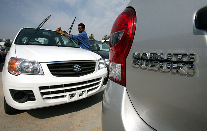 A worker cleans a parked car at the Maruti Suzuki's stockyard on the outskirts of Jammu.