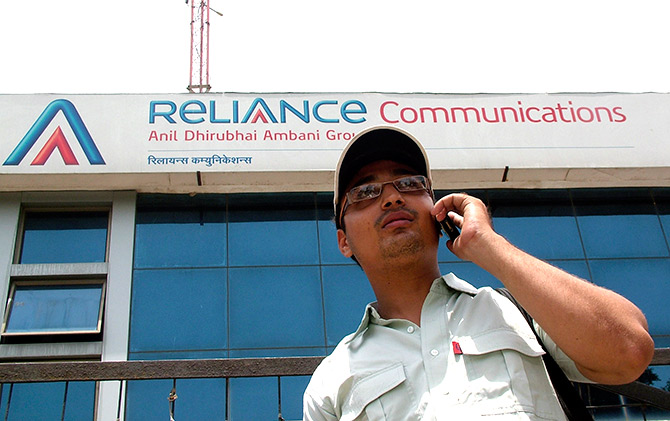 A man talks on a mobile phone in front of an advertisement for India's Reliance Communications in the northern Indian city of Mathura.