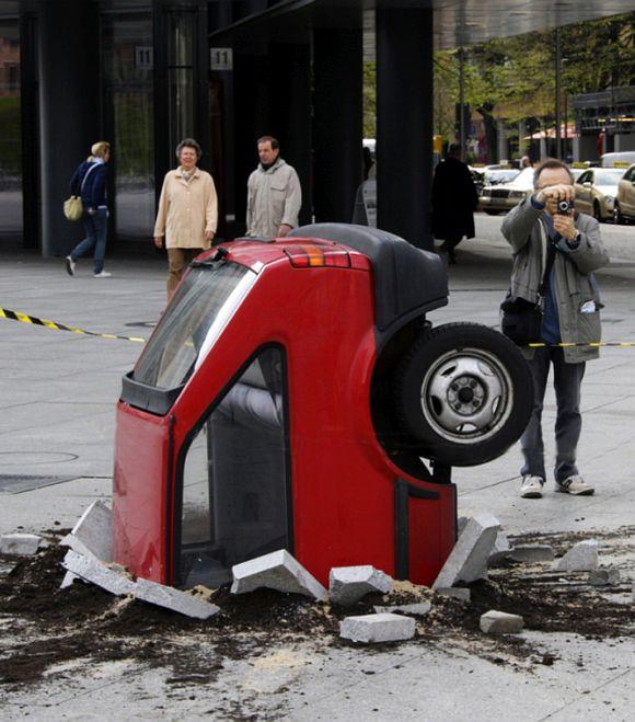 An unidentified artwork, showing a crashed car in the pavement.