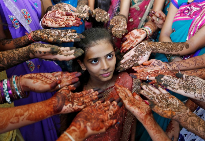 Schoolchildren show their hands decorated with henna paste during a henna competition to mark World Population Day in Ahmedabad July 11, 2014.