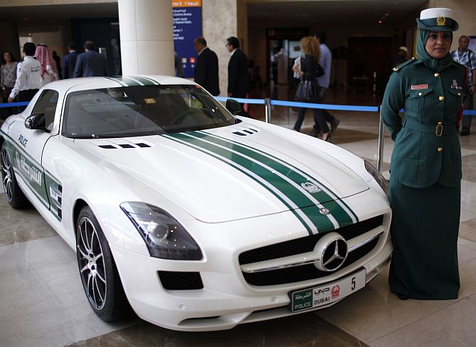 A police officer stands near a Mercedes car used by Dubai police.