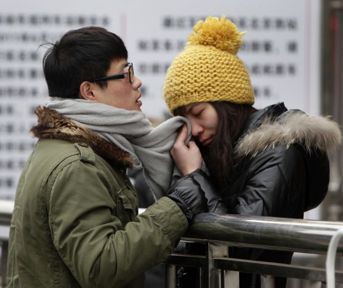 A woman wipes her tears with her partner's scarf as they part at Beijing west railway station during the Chinese New Year during which migrant workers get a chance to return to their home provinces.
