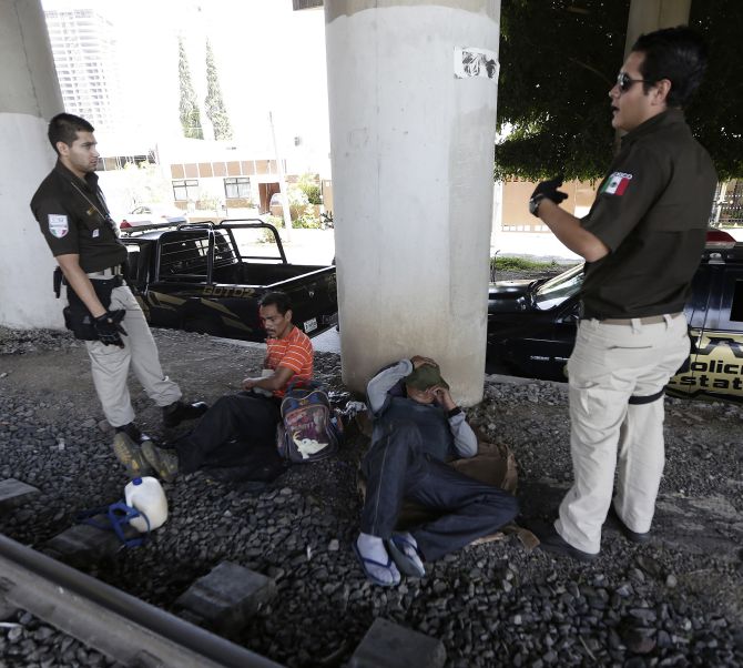 Immigration officers speak with Mexican men who were sleeping near a train track during a search operation for illegal immigrants.