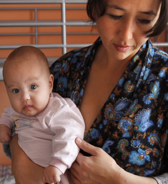 A Tajik migrant woman holds one of her twins in a shelter for women in crisis.