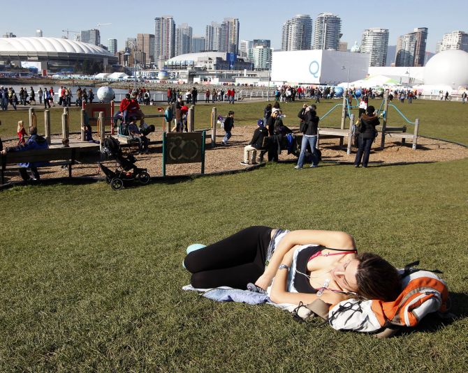 A woman sunbathes under blue skies at a park in Vancouver's False Creek during the Vancouver Winter Olympics.