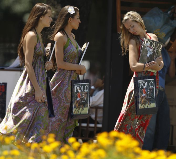Woman walk with polo magazines at the Campo Argentino de Polo in the Buenos Aires neighborhood of Palermo.