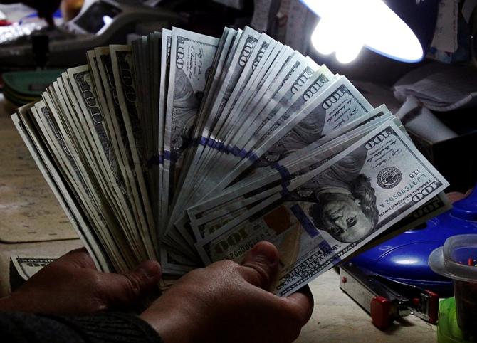 A money changer inspects U.S. dollar bills at a currency exchange.